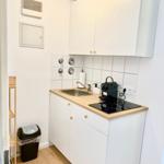 Küche mit Arbeitsplatte, Spüle, Kaffeemaschine und Schränken.