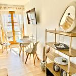 Essbereich mit Tisch, Stühlen und TV. Holzregal und Spiegel an der Wand.