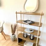 Hocker mit vier Ebenen, Spiegel darüber, Pflanze daneben.