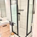 Badezimmer mit Duschkabine, Waschbecken und Spiegel.