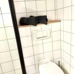 Badezimmer mit Toilette, Dusche und schwarzen Handtüchern auf Holzregal.