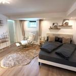 Schlafzimmer mit Doppelbett, Sessel und Fenster.