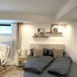 Schlafzimmer mit Doppelbett, Schaukelstuhl und Fenster.