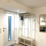 Eingangsbereich mit Schrank, Spiegel und Tür mit blauem Glas.