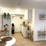 Küche mit Arbeitsplatte, Schränken und Pflanzen. Essbereich mit Tisch und Stühlen.