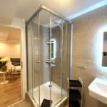 Duschkabine mit Glaswand, Waschbecken und Spiegel