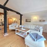 Living room with white sofa, wooden floor, and large beam.