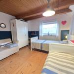 Room with two beds, sofa, wardrobe, and wooden floor.