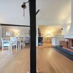 Living and dining area with wooden floor and fireplace. Dining area with table and chairs.