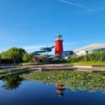 Red lighthouse with water slide next to a pond with water lilies.
