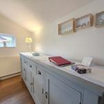 A room with a gray sideboard, a window, and three wall shelves.