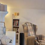 Room with armchair, bookshelf, and candle holder with seashells.