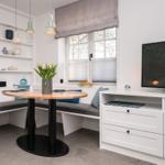 Essbereich mit Sitzbank, Tisch und Fernseher an der Wand.