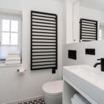 Moderne Badezimmer mit Dusche, Waschbecken und Heizkörper.