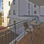 Terrasse mit Tisch und Stühlen, Blick auf Gebäude und Grünfläche.