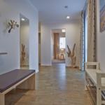 Flur mit Holzboden, Sitzbank und Wanddekoration. Durchgang zu Wohnraum mit Fenster.