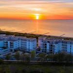 Modernes Gebäudekomplex am Meer bei Sonnenuntergang mit Blick auf das Wasser.