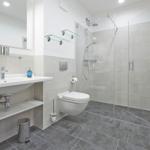 Badezimmer mit Dusche, Waschbecken und WC.