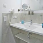 Badezimmer mit Waschbecken, Spiegel und Handtuchhalter.