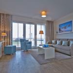 Wohnzimmer mit Sofa, Sessel und Balkonansicht.