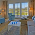 Wohnzimmer mit Sofa, Sessel und Balkonblick aufs Meer.