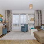 Wohnzimmer mit Sofa, Sessel, TV und Balkonzugang.