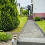 Gartenweg mit Stufen führt zur Haustür. Grünflächen und Sträucher umgeben den Eingang.