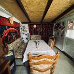 Esszimmer mit Holzstühlen, Tisch und Wandteppichen