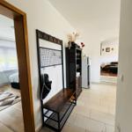 Eingangsbereich mit Garderobe, Bänke und Blick in Wohn- und Schlafzimmer.