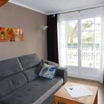Ein Wohnzimmer mit grauem Sofa, Holztisch und Fenster mit Blick auf Balkon.