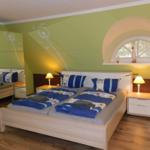 Doppelbett mit blauer Bettwäsche, Nachttische und Spiegelwand im Schlafzimmer.