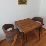 Holztisch mit zwei Stühlen und Wandbild im Raum.