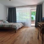 Schlafzimmer mit Bett, Tisch, Stühlen und Balkonansicht.