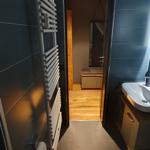 Badezimmer mit Dusche, Waschbecken und Heizkörper an der Wand.