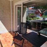 Terrasse mit Tisch und Stühlen, Blick auf Straße und Grünanlagen.