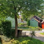 Rotes Haus mit Garten und Bäumen in ruhiger Straße