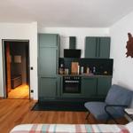 Küche mit grünen Schränken, Schlafzimmer mit Bett und Sessel, Essbereich mit Tisch und Stühlen.