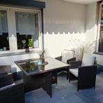 Terrasse mit Sitzgruppe, Tisch und Pflanzen. Wand und Boden sind sichtbar.