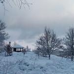Schneebedeckter Garten mit Pavillon und kahlen Bäumen im Winter.