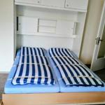 Zwei Betten mit blau-weiß gestreiften Bettwäsche unter einem weißen Schrank.