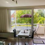 Essbereich mit Blick auf Balkon mit Tisch, Stühlen und Sonnenschirm.