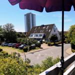 Blick vom Balkon auf Straße, Häuser und Hochhaus unter blauem Himmel.