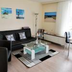 Wohnzimmer mit Sofa, Sitzgelegenheit und Essbereich. Wandbilder und Glas-Tisch.