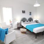 Schlafzimmer mit Doppelbett, zwei Stühlen und Tür zum Balkon.