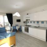 Wohnküche mit Sofa, Esstisch und Balkonzugang.