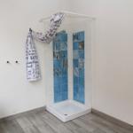 Dusche mit blauen Fliesen und Duschvorhang an der Wand.