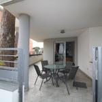 Terrasse mit Tisch und Stühlen, Sicht auf Wohnbereich und Baum.