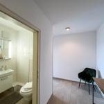 Badezimmer mit Waschbecken und Toilette. Nebenraum mit Stuhl und Schreibtisch.