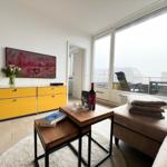 Wohnzimmer mit gelbem Schrank, Couch und Balkonansicht