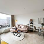 Wohn- und Essbereich mit Sofa, Tisch und Balkonansicht.